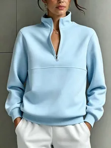 Close-up detail of light blue quarter-zip sweatshirt, featuring stand collar and ribbed hem.