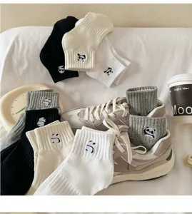 Detail view of cute panda embroidered cotton short socks in assorted colors with sneakers.