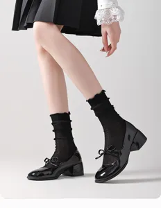 Primer plano de calcetines negros de malla transparente con volantes y zapatos de cuero clásico.