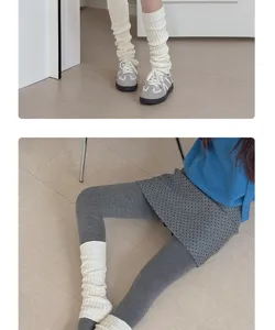 Detailed view of white knitted leg warmers showing texture and styling for winter outfits.