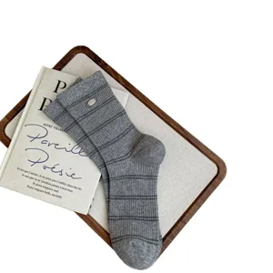 Grey striped cotton mid-tube socks with metal charm for women, vintage style casual wear.