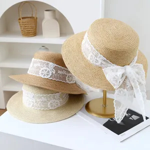 Detail view of summer women's flat top straw hat featuring delicate white lace ribbon bow.