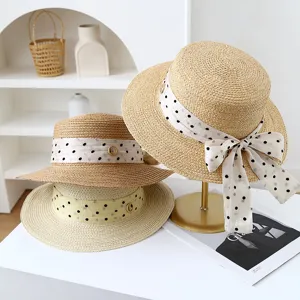 Detail view of summer straw hat with polka dot ribbon and decorative ring, beach style.