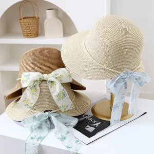 Detail of women summer straw sun hat with pearl trim and floral ribbon bow for beach vacation.