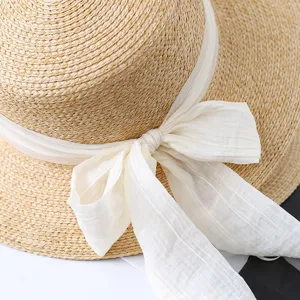 Close-up detail of women summer flat top straw sun hat with white bow ribbon beach wear