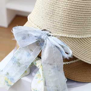 Detailed close-up of women summer straw sun hat with pearl decor and blue ribbon bow.