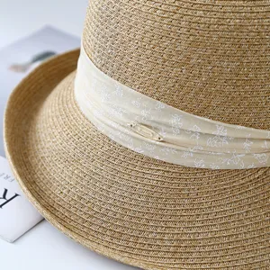 Zomerse geweven strohoed voor dames met bedrukt lint en metalen detail voor strandzonbescherming.