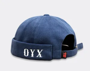 Blaue Kord-Dockermütze mit weißer OYX-Bestickung und Metallschnalle Detailaufnahme