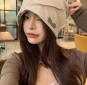 Detailaufnahme einer stilvollen, slouchy Strickmütze in Beige mit Metall-Logo für Streetwear.