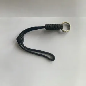 Vista detallada de un cordón llavero de paracord negro con anillo metálico y hebilla.