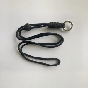 Detalle de cordón de paracaídas negro con textura tejida y anillo de metal para exteriores.