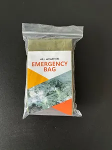 Detalle de saco de dormir de emergencia, manta térmica portátil en bolsa sellada.