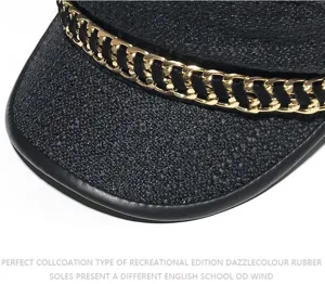 Vista ravvicinata dell'elegante berretto piatto in tweed nero con dettaglio catena d'oro.