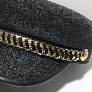 Elegante berretto piatto nero in tweed da donna con dettaglio di catena dorata alla moda.