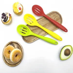 Silicone slotted spoon detail view, showing vibrant green, yellow and red cooking utensils.