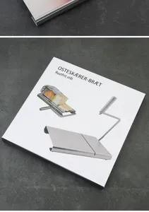 Stainless steel cheese slicer detail view with packaging box showing metal wire cutting design.