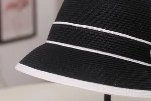 Dettaglio in primo piano di cappello di paglia nero a righe bianche, protezione solare.