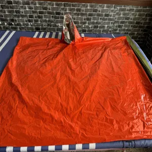 Poncho impermeable de emergencia naranja y saco de dormir de supervivencia para acampar al aire libre.