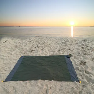 Waterproof outdoor beach blanket in dark green with handy storage bag, perfect for camping trips.