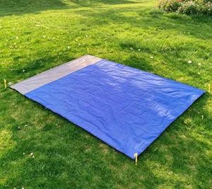 Detailed view of the waterproof camping picnic ground sheet spread on green grass outdoors.