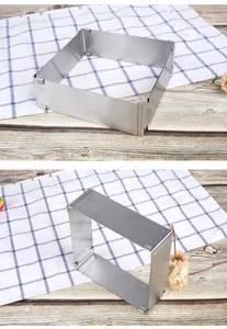 Detail view of adjustable stainless steel square mousse cake baking mold on plaid cloth and wood.