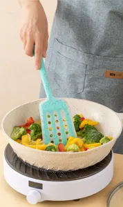 Detailed view of teal speckle silicone slotted spatula cooking vegetables in nonstick pan.