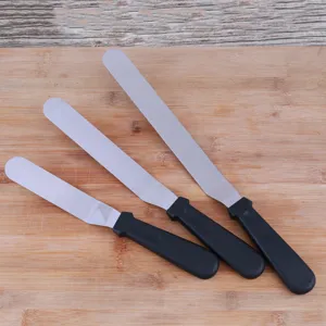 Stainless steel cake spatula detail showing three baking tools with ergonomic black handles.