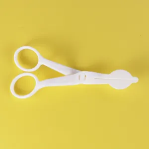 Vue détaillée des ciseaux de transfert de fleurs de gâteau en plastique blanc, outil de pâtisserie.