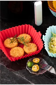 Silicone air fryer liner detail shot, red square basket with hash browns and rosemary.
