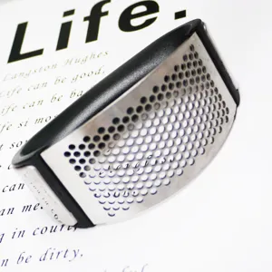 Stainless steel curved garlic press detail, ergonomic manual mincer for kitchen use.