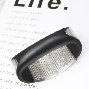 Stainless steel curved garlic press closeup, ergonomic black handle, kitchen tool detail.