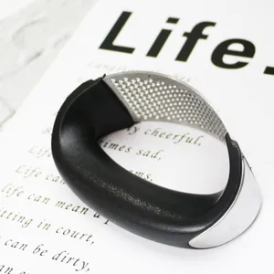 Stainless steel curved garlic press detail view, manual kitchen mincer tool for home.