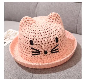 Cute pink knitted baby sun hat with adorable cat ears and embroidered face for summer outdoor.
