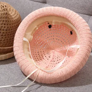 Cute pink knitted baby sun hat with straps, breathable hollow woven infant cap for summer outdoor.