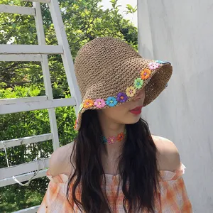 Primo piano del cappello di paglia estivo con dettagli floreali colorati lavorati all'uncinetto.