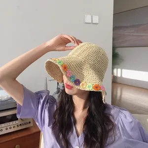 Vista dettagliata cappello di paglia donna secchiello con fiori colorati all'uncinetto.