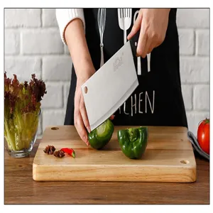 Stainless steel kitchen knife detail showing sharp blade and ergonomic handle cutting vegetables.