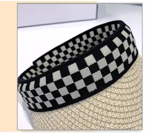 Nahaufnahme des Stroh-Sonnenschutzes mit schwarz-weißem Karomuster-Gummiband Detail.