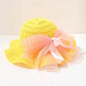 Niedlicher gelber Spitzen-Sommerhut mit rosa Mesh-Schleife, süßes Kinder-Accessoire-Detail.