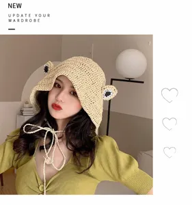Charming straw bucket hat with cute frog eyes and chin ties, perfect for summer beach and sun.