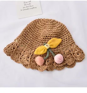 Détail chapeau de paille enfant, design tissé avec cerises et nœud pour l'été.