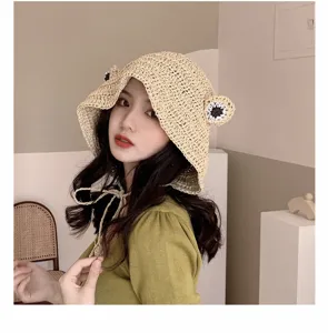 Detailed view of the cute frog-themed handmade straw hat, showing crochet texture and eyes.
