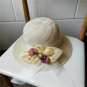 Cappello di paglia beige traforato con elegante fiore in nastro e dettaglio di perla.