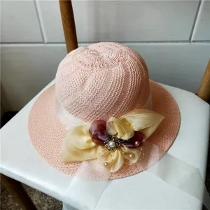 Cappello da sole estivo traforato da donna con elegante nastro e decorazione di perle.