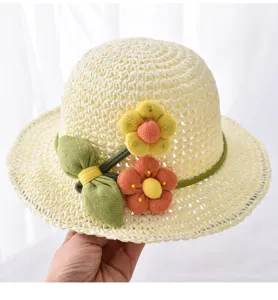 Nahaufnahme Detail des süßen Kinderstrohhats mit Strickblumen und grünen Blättern Sommer.