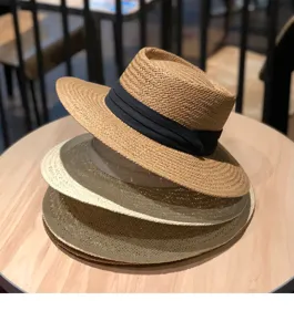 Detailansicht des handgeflochtenen Sommer-Strohhutes mit breiter Krempe und schwarzem Band am Strand.