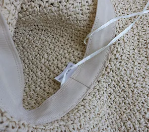 Primo piano dell'interno del cappello di paglia da donna con trama intrecciata e cinturino.