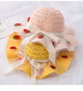 Dettaglio cappello di paglia per bambini, cappello sole estivo con pizzo e fragole.