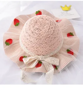 Vista dettagliata di un cappello di paglia per bambini con fragole all'uncinetto e fiocco.
