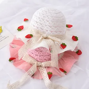 Grazioso cappello di paglia estivo per bambini con fiocco in pizzo e bellissime fragole.